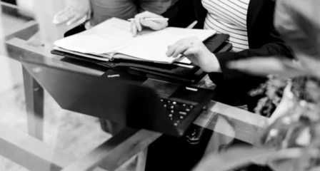 Hands with a notebook and documents beside a laptop