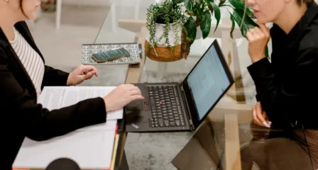 Open notebook and laptop on a glass meeting table