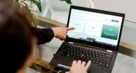 Hand pointing at information on a laptop screen