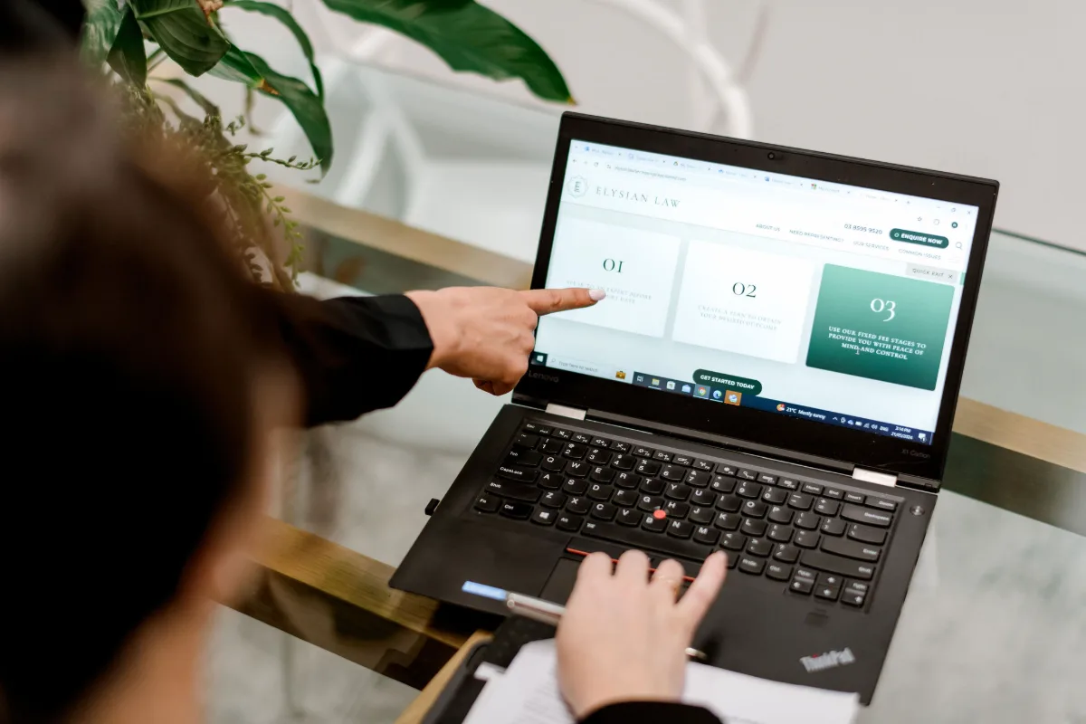 Hand pointing at information on a laptop screen